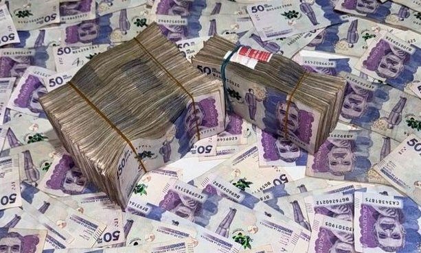 Dos fajos de billetes colombianos de 50.000 pesos atados con bandas elásticas sobre más billetes esparcidos